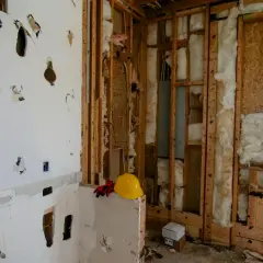Chantier en cours, murs ouverts révélant l'isolant. Attention, la laine de bois peut présenter un danger si mal manipulée. Casque et gants de protection à proximité.