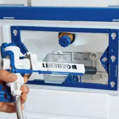 Main d'un plombier installant le mécanisme d'une chasse d'eau encastrée Geberit.
