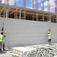 Chantier de construction : des ouvriers installent des blocs de béton cellulaire pour l'isolation d'un mur extérieur.