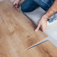 Pose d'un parquet stratifié imitation bois. Un homme installe une lame de revêtement de sol.
