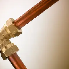 Un coude en laiton relie deux tuyaux en cuivre. Ce raccord per cuivre assure une connexion solide pour le système de plomberie.