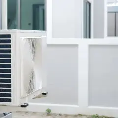 Unité extérieure de pompe à chaleur installée sur un mur blanc, prête à assurer le confort de la maison.