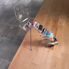 Une jonction carrelage parquet sans barre de seuil, avec une chaise transparente et des livres.