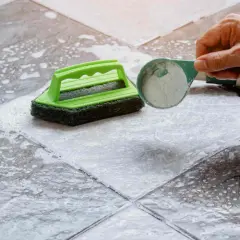 Nettoyer carrelage mural encrassé avec une éponge verte et une poudre nettoyante.