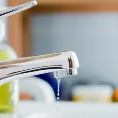 Gouttes d'eau tombant d'un robinet mitigeur qui fuit au col. Un problème de plomberie à régler.