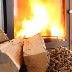 Bûches et granulés de bois prêts pour le chauffage. Le feu crépite dans le poêle, promettant une douce chaleur.