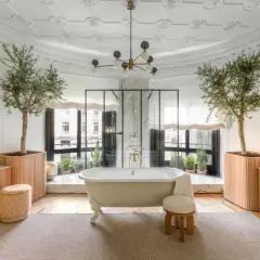 Salle de bain luxueuse avec baignoire îlot, arbres d'olivier et vue sur la ville. L'évacuation baignoire îlot est discrète.