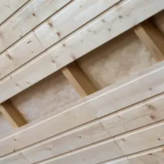 Pose lambris en bois clair, montrant la structure sous-jacente avec des tasseaux et de l'isolant.