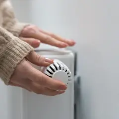 Mains mains sur un radiateur, ajustant le thermostat pour contrôler le prix du chauffage au gaz.