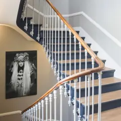 Habillage mur cage d'escalier avec un portrait vintage. L'escalier est orné d'une rampe en bois et de barreaux blancs.