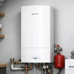 Installation chaudiere gaz moderne dans une buanderie. L'appareil blanc est fixé au mur, entouré de tuyaux et d'un réservoir rouge.