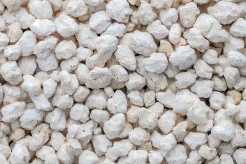 Gros plan sur des granulés blancs et irréguliers, typiques de la perlite utilisée pour l'isolation.