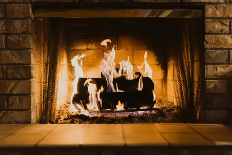 Un feu de cheminée crépite joyeusement, ses flammes dansantes illuminent les briques et les bûches. Les signes d'un hiver douillet.