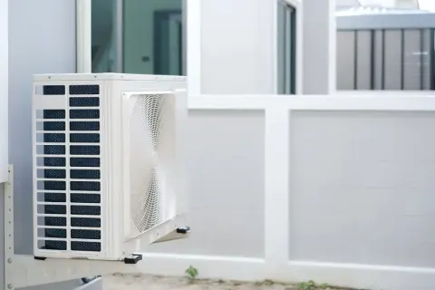 Unité extérieure de pompe à chaleur installée sur un mur blanc, prête à assurer le confort de la maison.