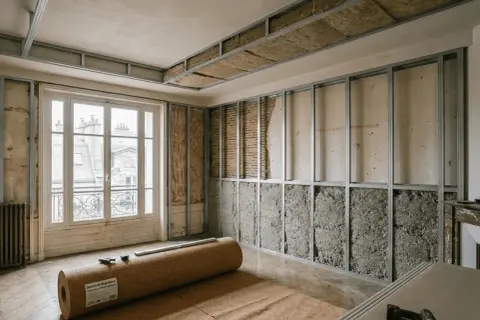 Rénovation d'une pièce avec ossature métallique pour l'isolation phonique. Rouleau de liège au sol, murs et plafond en cours d'isolation.