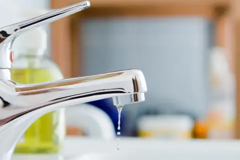 Gouttes d'eau tombant d'un robinet mitigeur qui fuit au col. Un problème de plomberie à régler.
