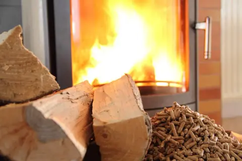 Bûches et granulés de bois prêts pour le chauffage. Le feu crépite dans le poêle, promettant une douce chaleur.