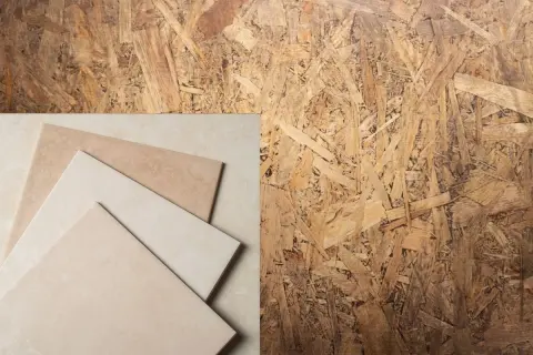 Un panneau de pose OSB avec des carreaux de céramique beiges et marron disposés en diagonale.