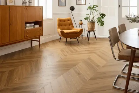 Un salon moderne avec un **pose parquet point de hongrie** en bois clair, un fauteuil moutarde et un buffet vintage.
