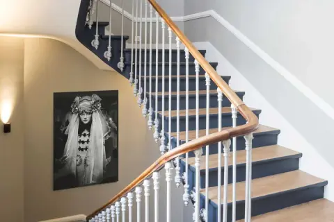 Habillage mur cage d'escalier avec un portrait vintage. L'escalier est orné d'une rampe en bois et de barreaux blancs.