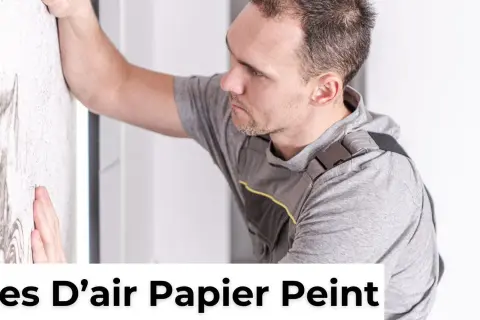 Un homme en tenue de travail lisse un mur pour enlever une bulle d'air dans du papier peint sec.