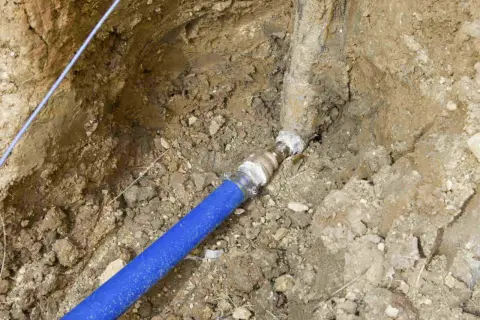 Raccordement d'une canalisation eau enterrée, respectant les normes. Le tuyau bleu est relié à une conduite plus ancienne.