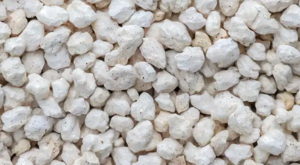 Gros plan sur des granulés blancs et irréguliers, typiques de la perlite utilisée pour l'isolation.