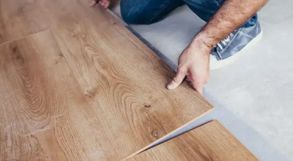 Pose d'un parquet stratifié imitation bois. Un homme installe une lame de revêtement de sol.