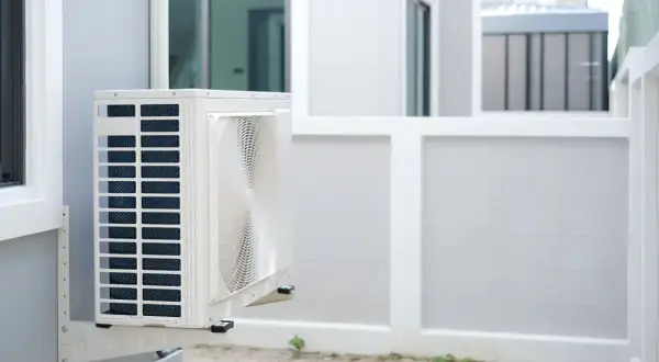 Unité extérieure de pompe à chaleur installée sur un mur blanc, prête à assurer le confort de la maison.