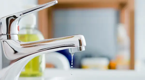 Gouttes d'eau tombant d'un robinet mitigeur qui fuit au col. Un problème de plomberie à régler.