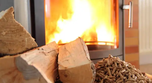 Bûches et granulés de bois prêts pour le chauffage. Le feu crépite dans le poêle, promettant une douce chaleur.