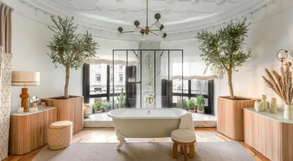 Salle de bain luxueuse avec baignoire îlot, arbres d'olivier et vue sur la ville. L'évacuation baignoire îlot est discrète.