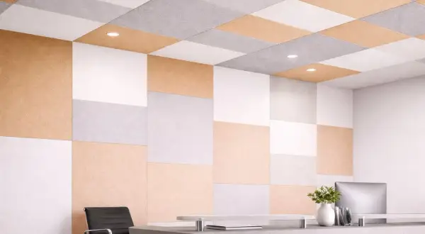 Panneaux acoustiques colorés, blancs, gris et beige, formant un motif à damier sur le mur et le plafond, parfaits pour isoler phoniquement un mur.