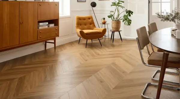 Un salon moderne avec un **pose parquet point de hongrie** en bois clair, un fauteuil moutarde et un buffet vintage.