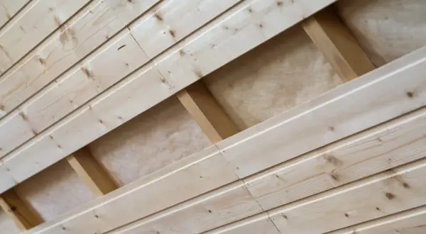 Pose lambris en bois clair, montrant la structure sous-jacente avec des tasseaux et de l'isolant.