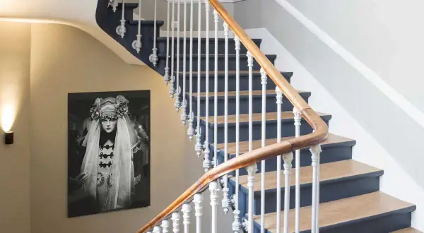 Habillage mur cage d'escalier avec un portrait vintage. L'escalier est orné d'une rampe en bois et de barreaux blancs.