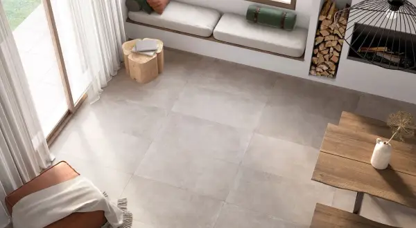 Un salon lumineux avec un **schema plancher bois** discret, un banc près de la fenêtre, un pouf et une table en bois.