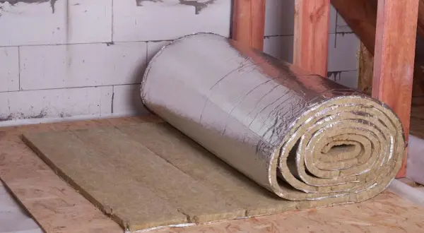 Rouleau d'isolant thermique à faible épaisseur, prêt à être posé sur un plancher en bois. Idéal pour une isolation performante et discrète.
