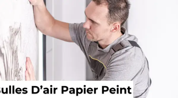 Un homme en tenue de travail lisse un mur pour enlever une bulle d'air dans du papier peint sec.