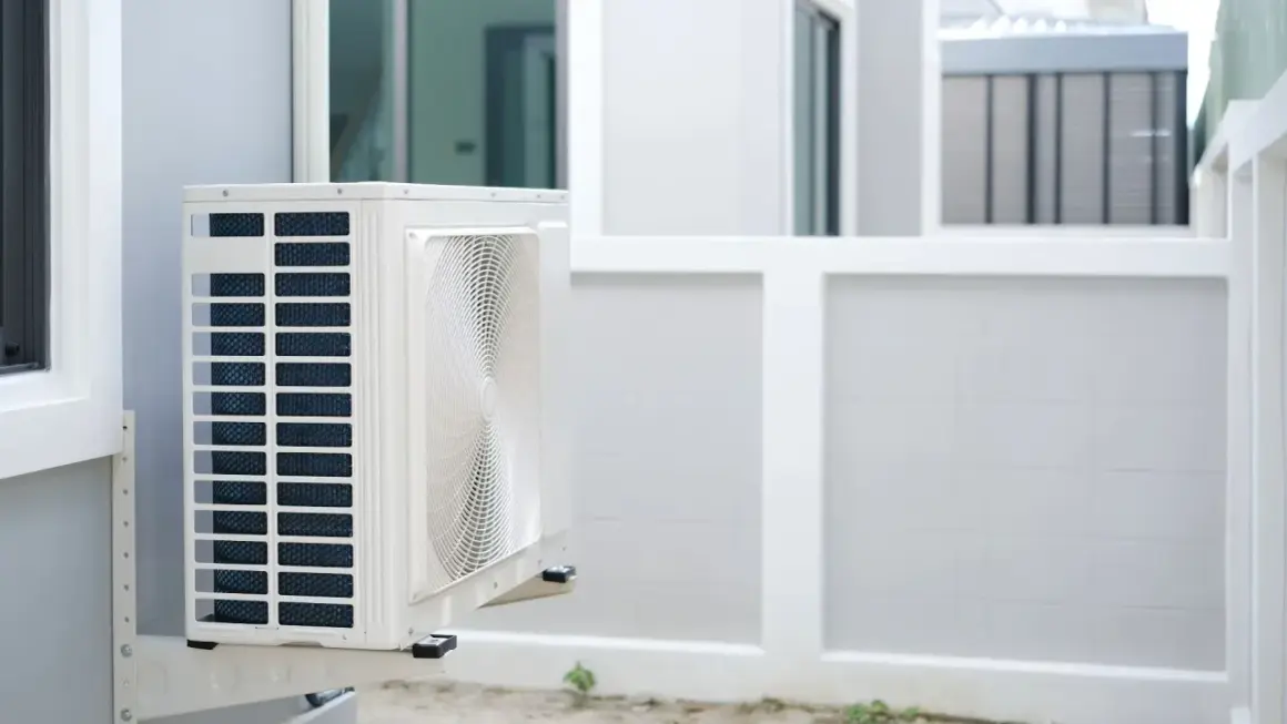 Unité extérieure de pompe à chaleur installée sur un mur blanc, prête à assurer le confort de la maison.
