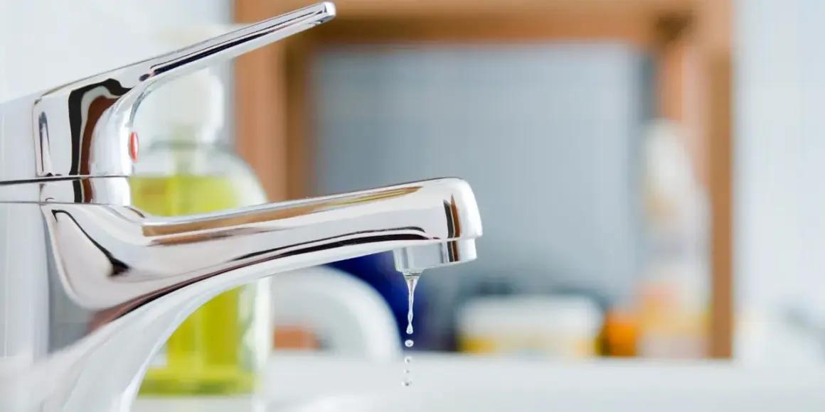 Gouttes d'eau tombant d'un robinet mitigeur qui fuit au col. Un problème de plomberie à régler.