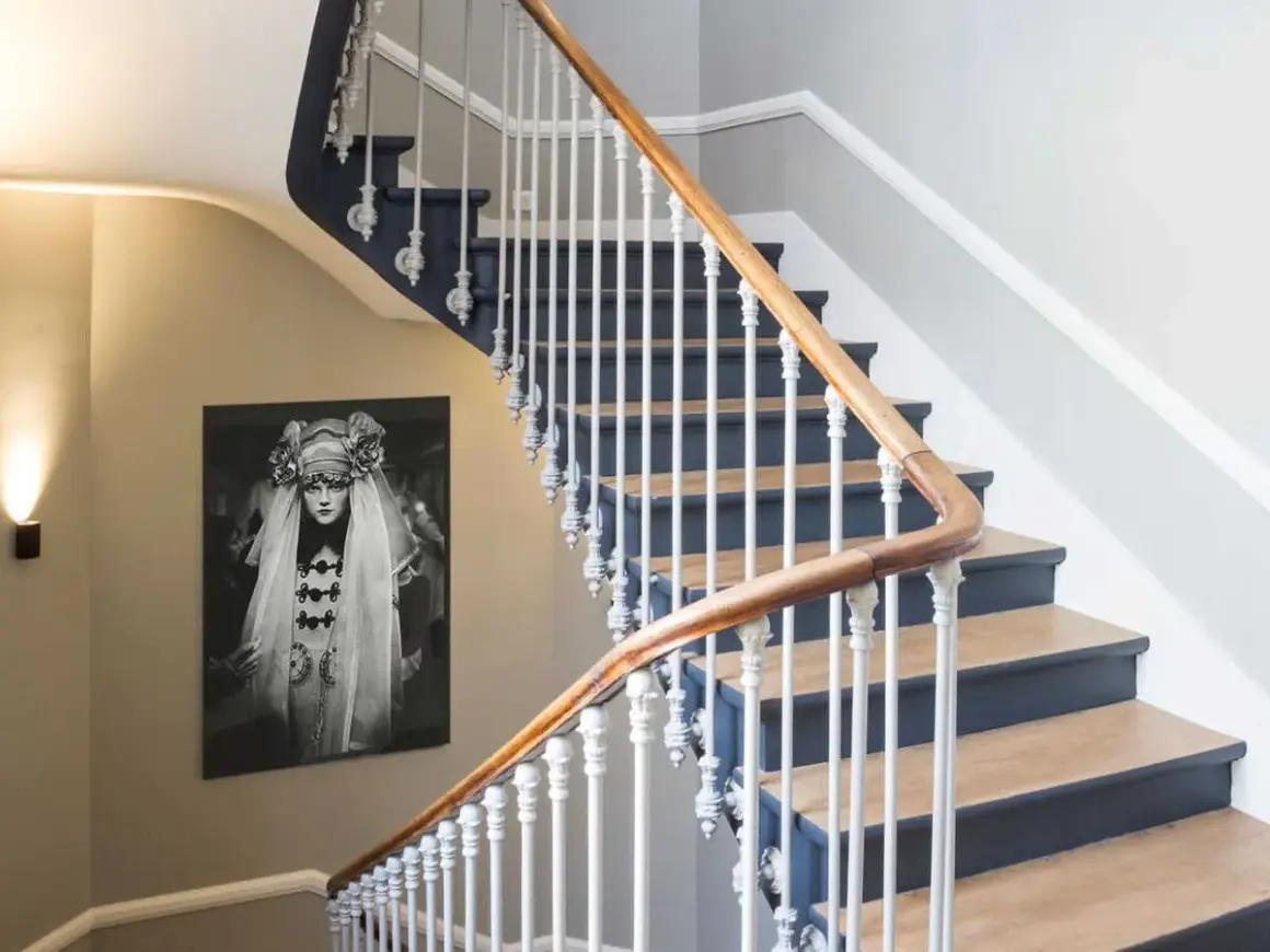 Habillage mur cage d'escalier avec un portrait vintage. L'escalier est orné d'une rampe en bois et de barreaux blancs.