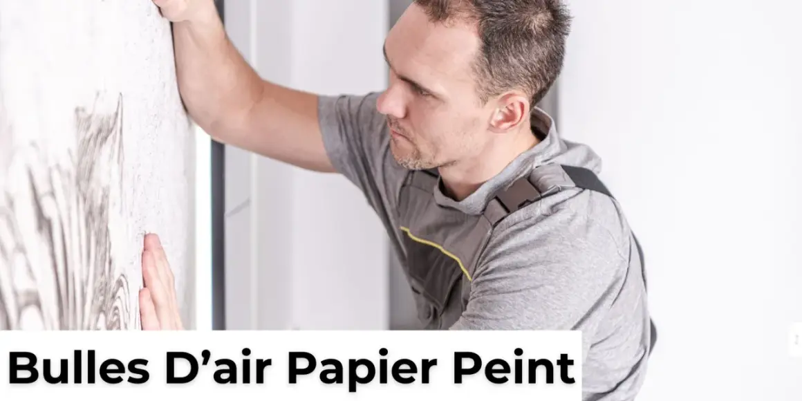Un homme en tenue de travail lisse un mur pour enlever une bulle d'air dans du papier peint sec.
