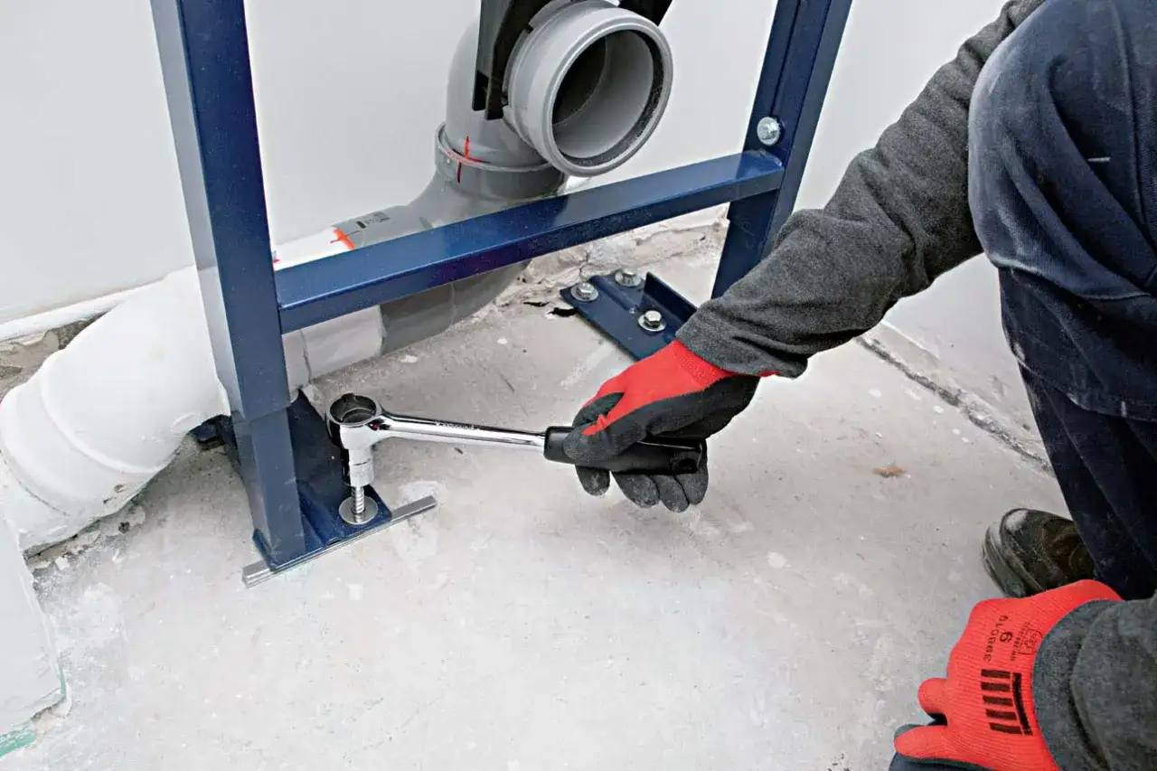 Main tenant utilise une cl&eacute; pour fixer le b&acirc;ti-support lors de l'installer wc suspendu.