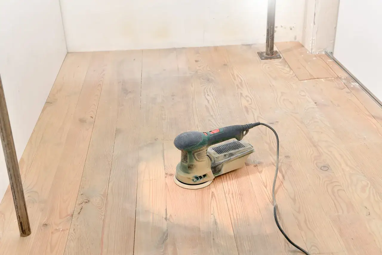 Une ponceuse orbitale est pr&ecirc;te &agrave; poncer le parquet en bois clair.