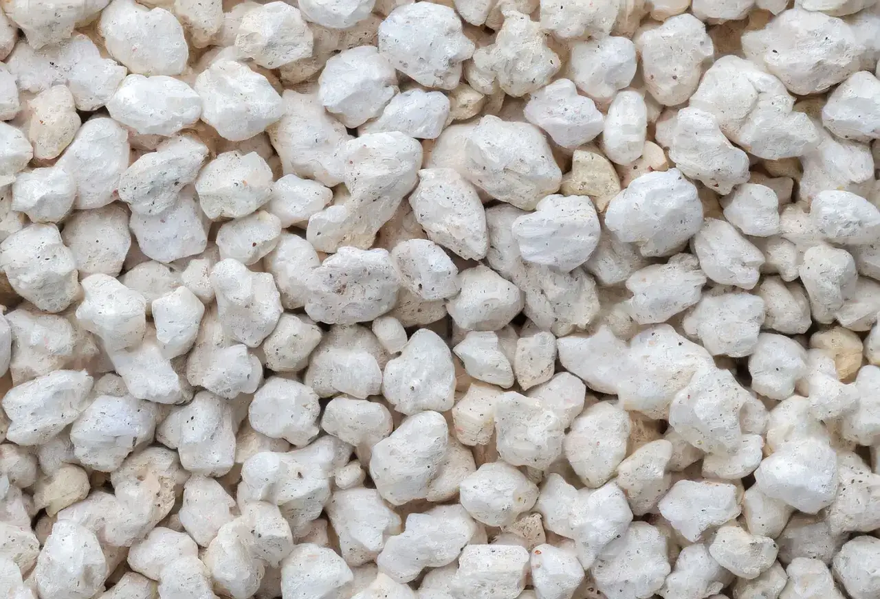 Gros plan sur des granulés blancs et irréguliers de perlite, un matériau léger utilisé pour l'isolation et l'horticulture.