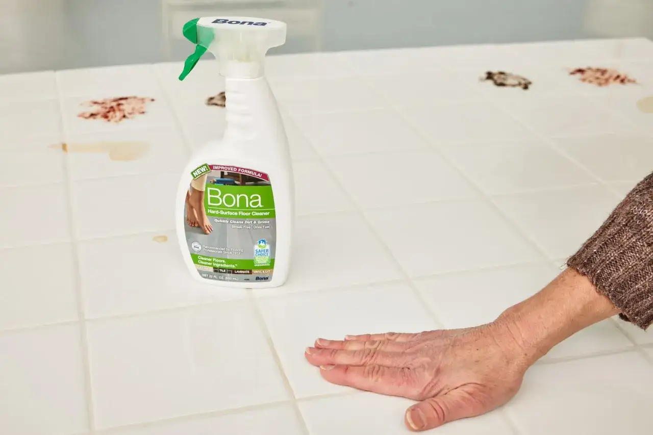 Une main nettoie du carrelage taché avec le meilleur produit pour faire briller le carrelage, le nettoyant Bona.