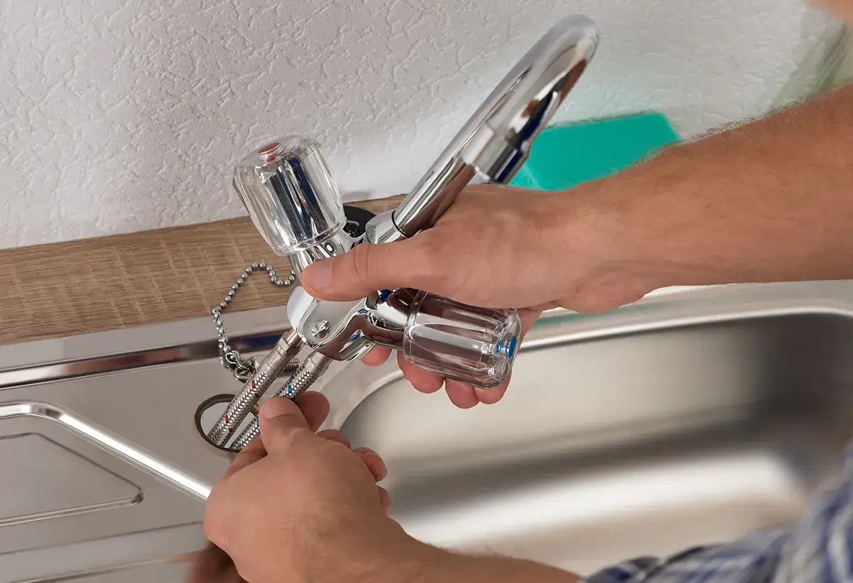Mains pour changer un mitigeur de cuisine, connectant les tuyaux flexibles &agrave; l'&eacute;vier.