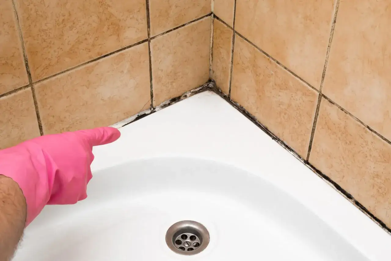Main rose gant pour nettoyer joint salle de bain moisi.