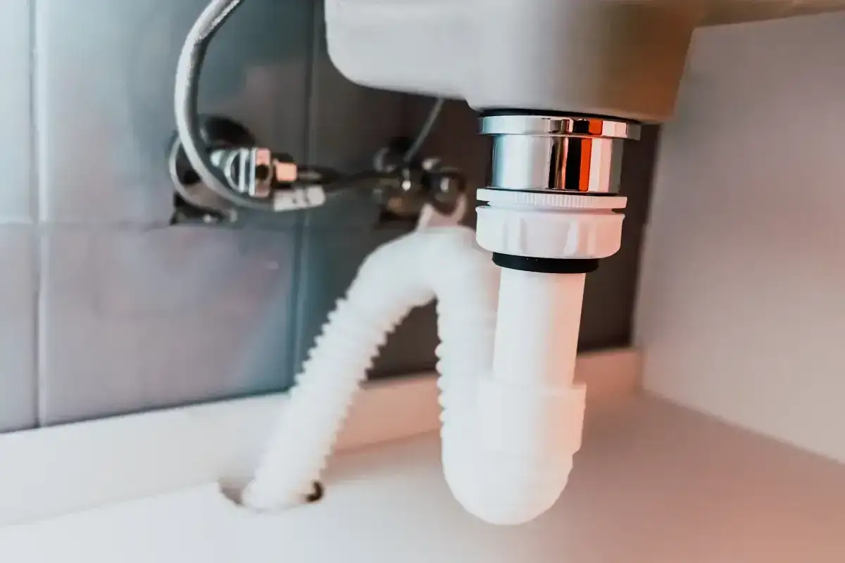 Détail du schema montage bonde lavabo : raccordement du siphon et du tuyau d'évacuation flexible sous un évier.